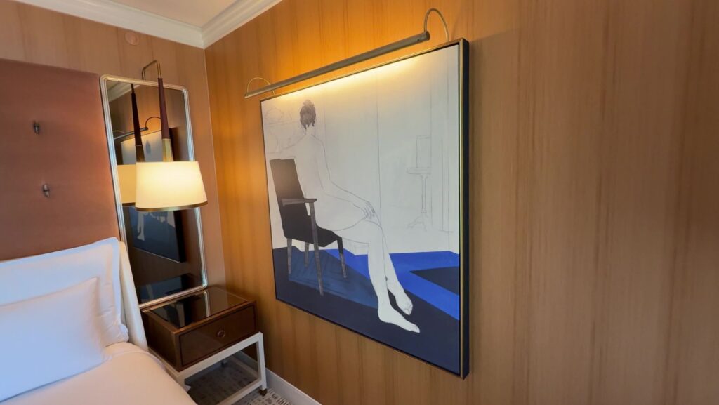 A painting of a man sitting on a chair, that has it's own illumination built in. 