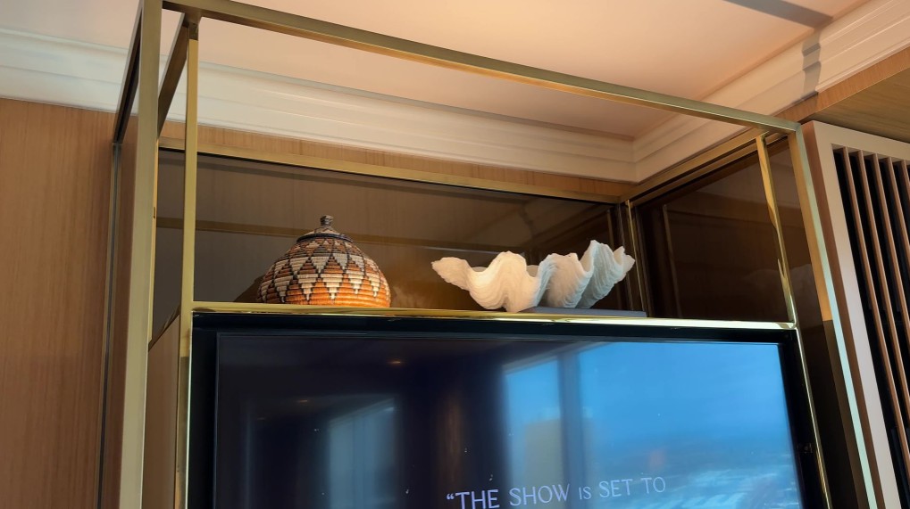 Two artifact decor pieces, a shell and a jar above the TV, illuminated from below. 