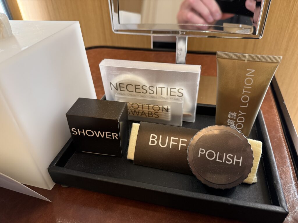 A tray in the bathroom with hygeine items like cotton swabs, a shower cap, and shoe polish. 