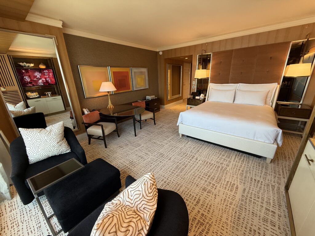 Angle of the room that shows the king bed on the right, and a coffee table against the wall to the left. 