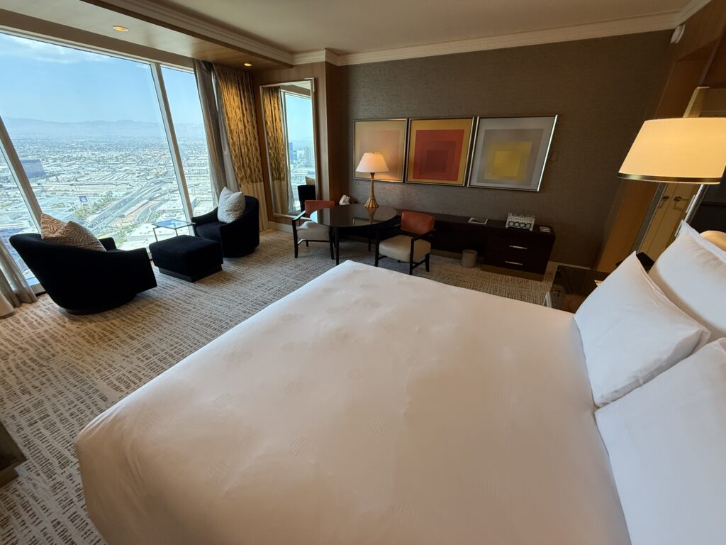 Angle of the room that shows the bed in the foreground and the window/coffee table in the background. 