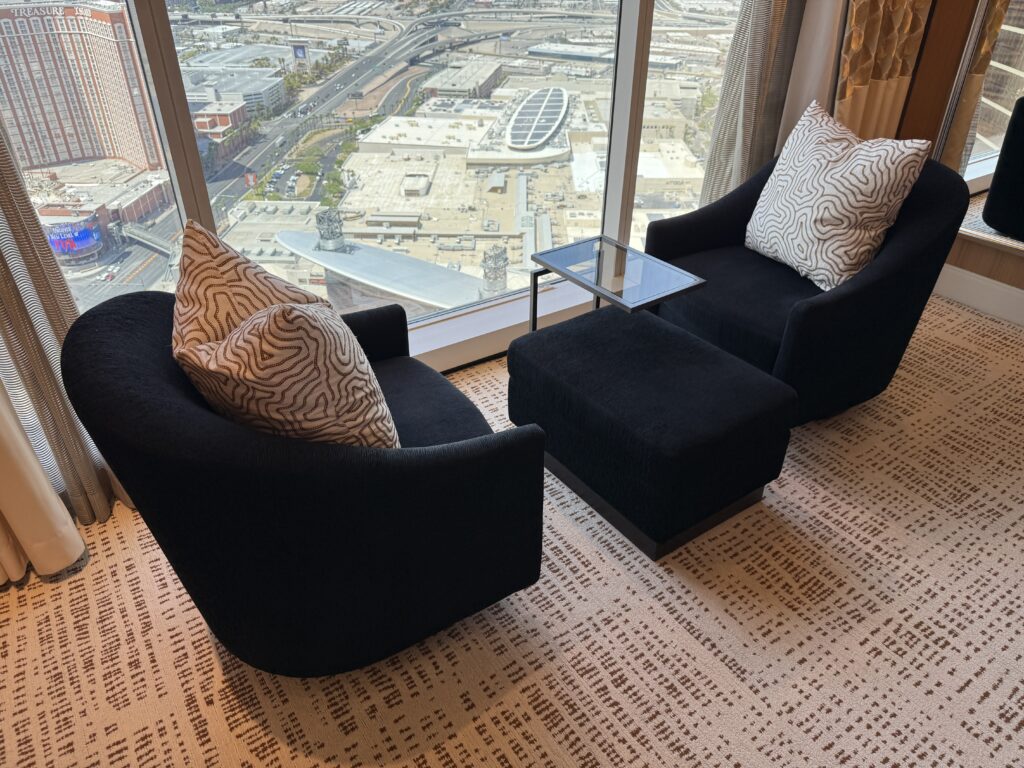 Two swiveling chairs with a small table between them, positioned in front of the window. 