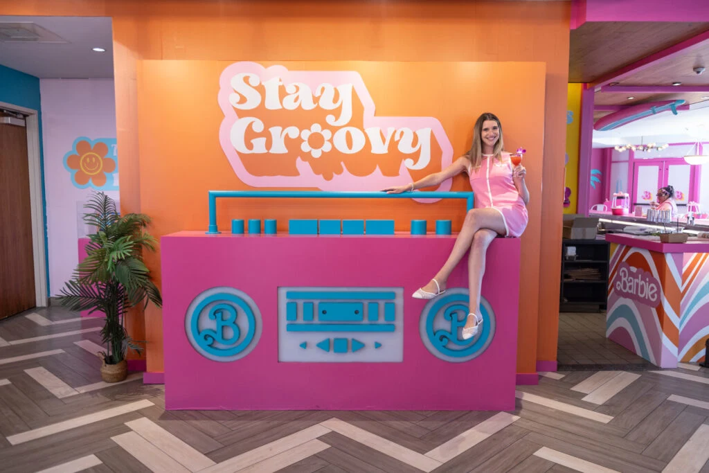 A photo op of a woman sitting on top of a pink boombox.