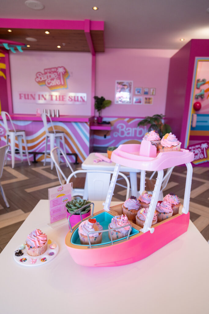 A toy boat on a table with 9 cupcakes on it.