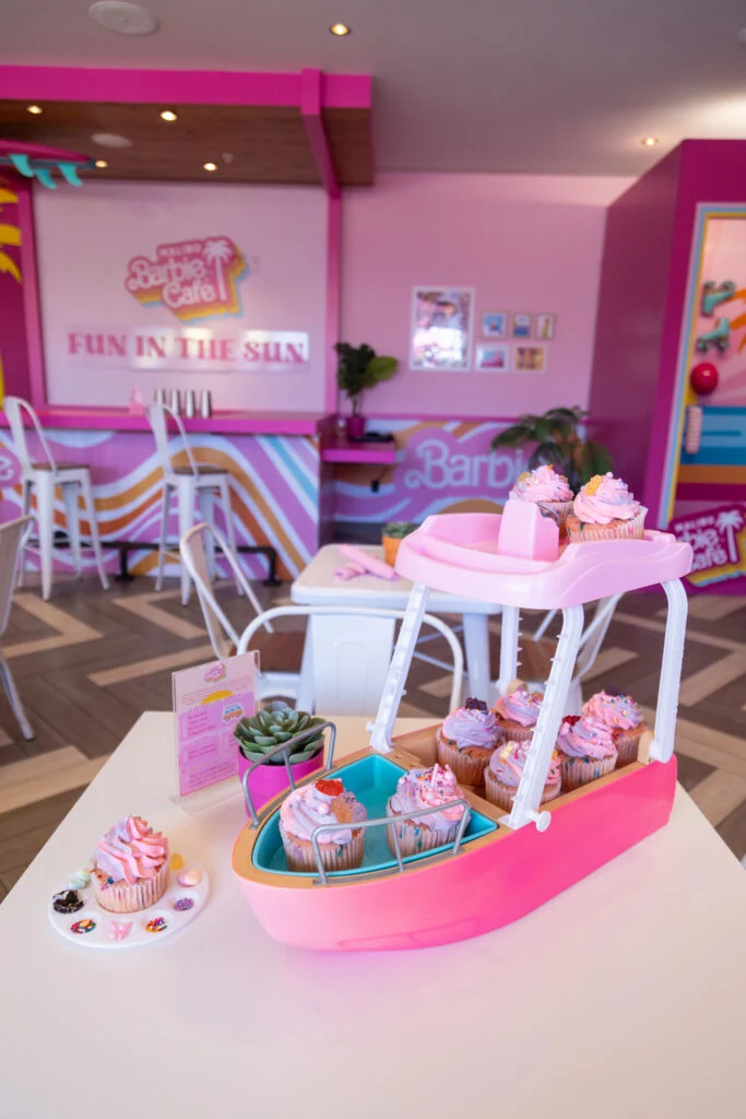 A toy boat on a table with 9 cupcakes on it.