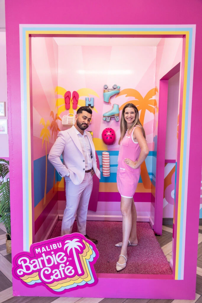 Two people posing in a photo opp designed to look like they are barbie dolls in a box. 