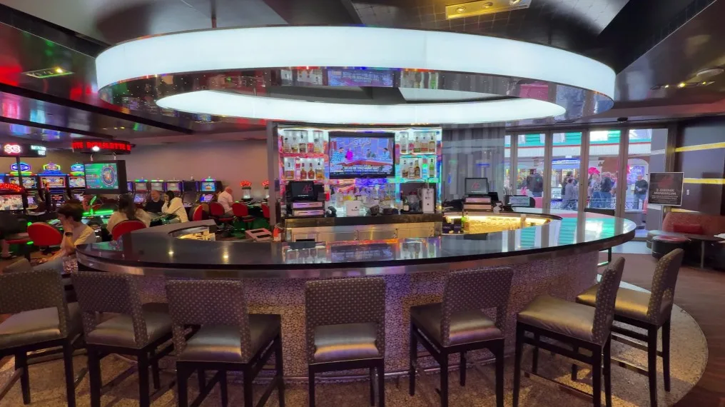 A casino bar with a large, circular, light fixture above. 