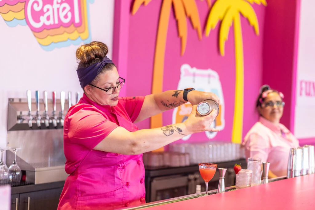 A bartender pours a cocktail behind the bar. 