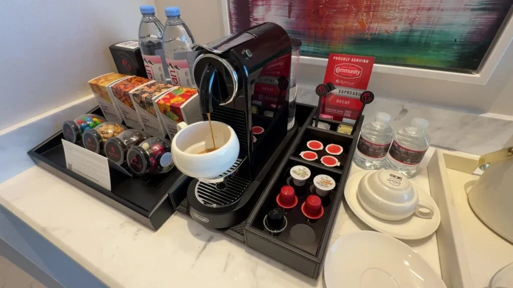 A single cup coffee brewer actively brewing coffee into a white mug. 