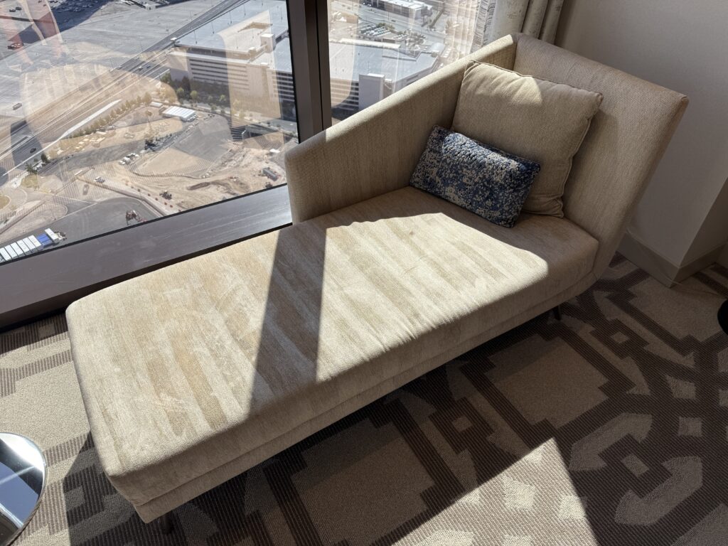 A couch next to the window, with visible vaccuum lines.