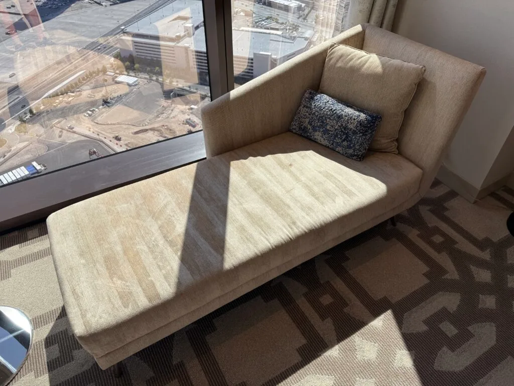 A couch next to the window, with visible vaccuum lines. 