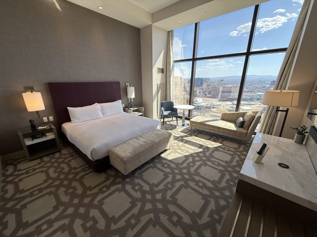 Wide angle shot of the room with a king bed, and floor to ceiling windows in the background.