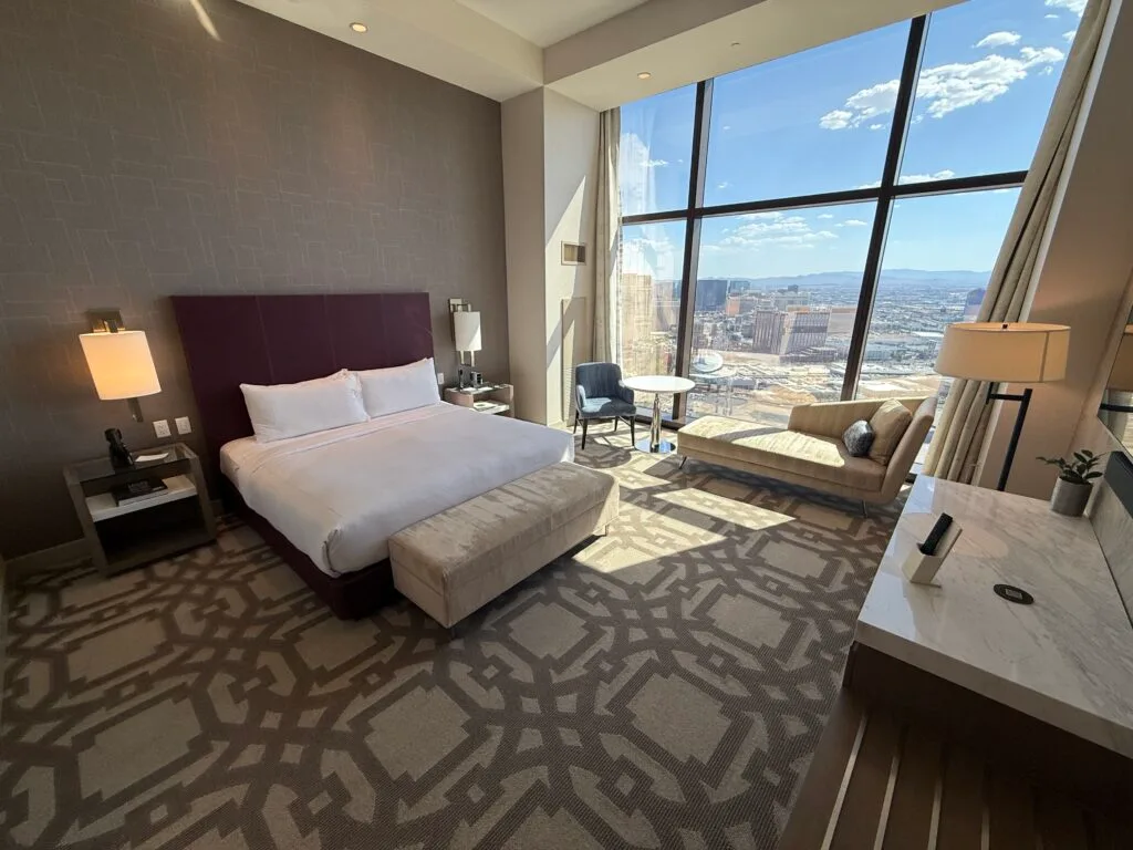 Wide angle shot of the room with a king bed, and floor to ceiling windows in the background. 