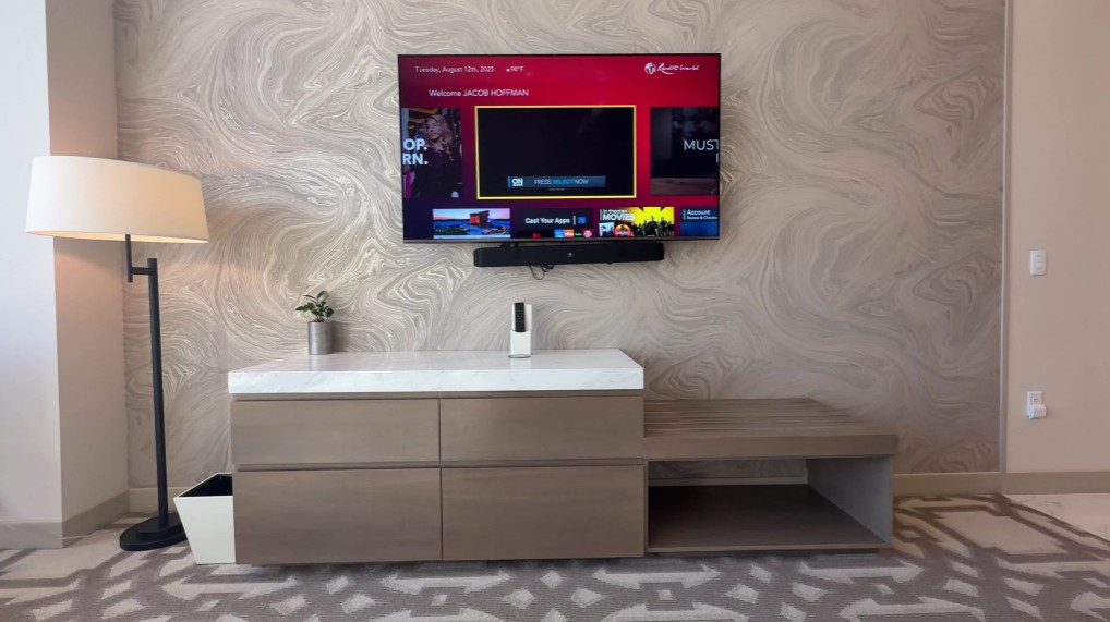 TV hanging on the wall with a crooked sound bar mounted underneath.