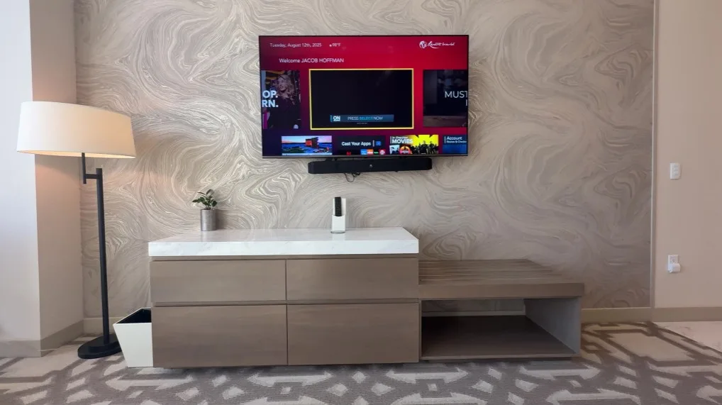 TV hanging on the wall with a crooked sound bar mounted underneath. 