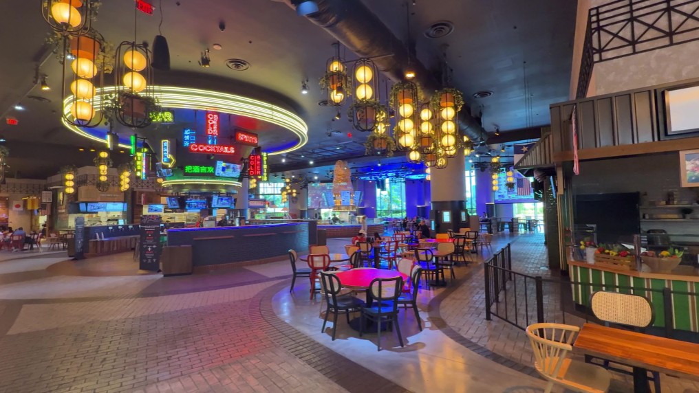 Neon signs over a center bar in the food hall.