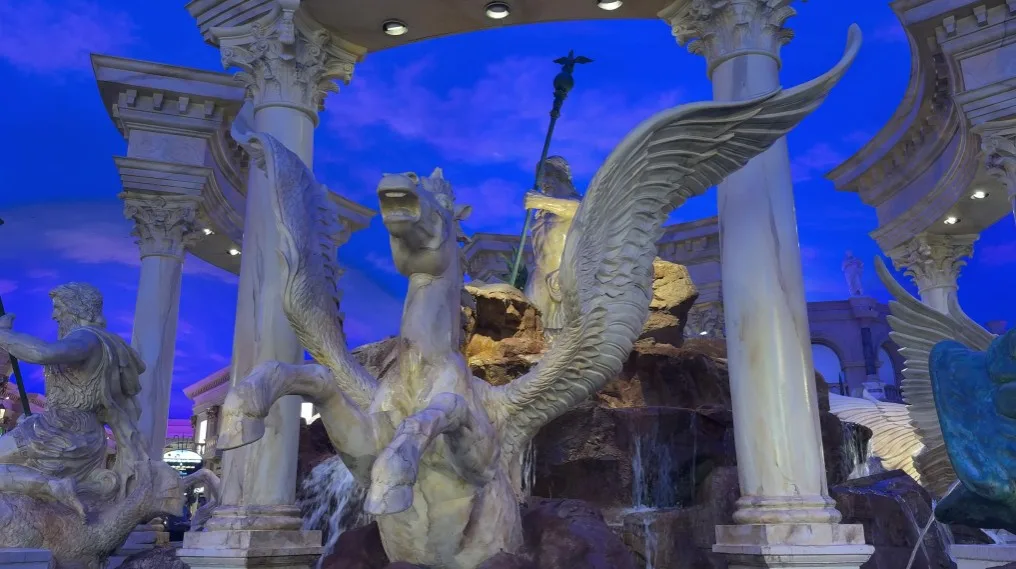 A statue of a horse, visibly neighing, with colums and a faux blue sky behind it.