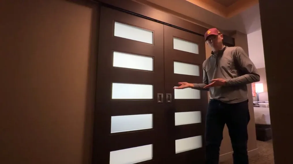 A decorative door made of dark wood, with fogged glass windows that allow light through. 