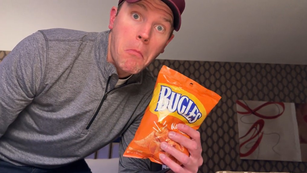 Me, in front of the camera holding a bag of cheddar Bugles.