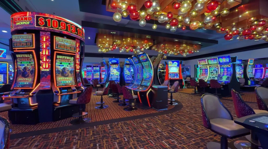 Slots on the casino floor, and decorative glass lighting overhead. 