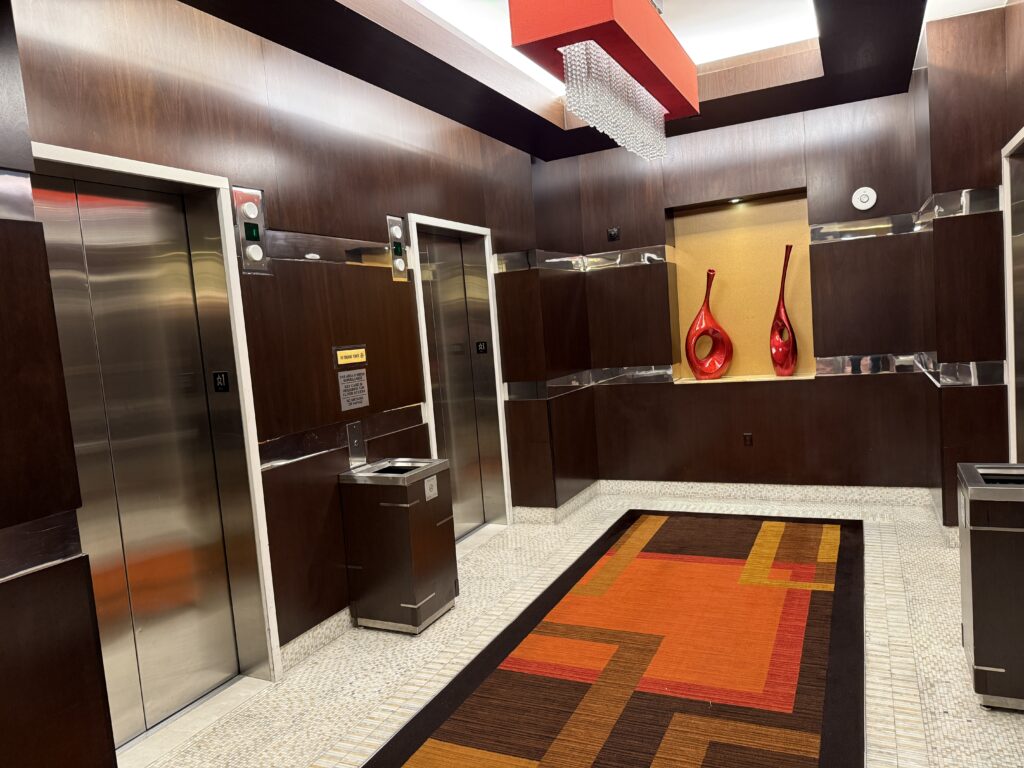 Ground floor elevator lobby, which has decorative overhead lighting, dark wood features, and vases on display in the background.