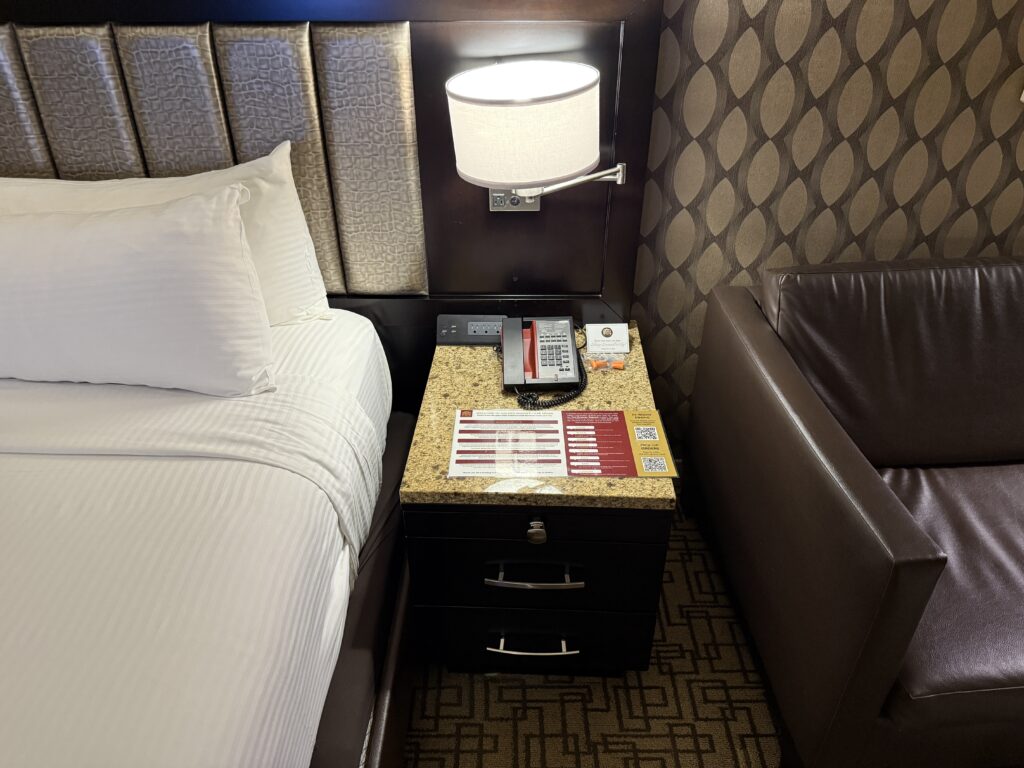 End table with an illuminated lamp atop it along with a charging bank.