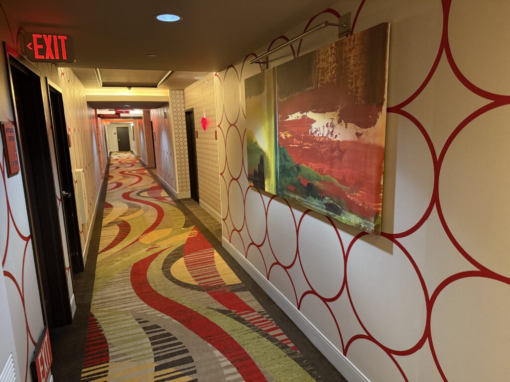 Hotel Hallway, with a painting on the wall, and a circle pattern on the wallpaper.