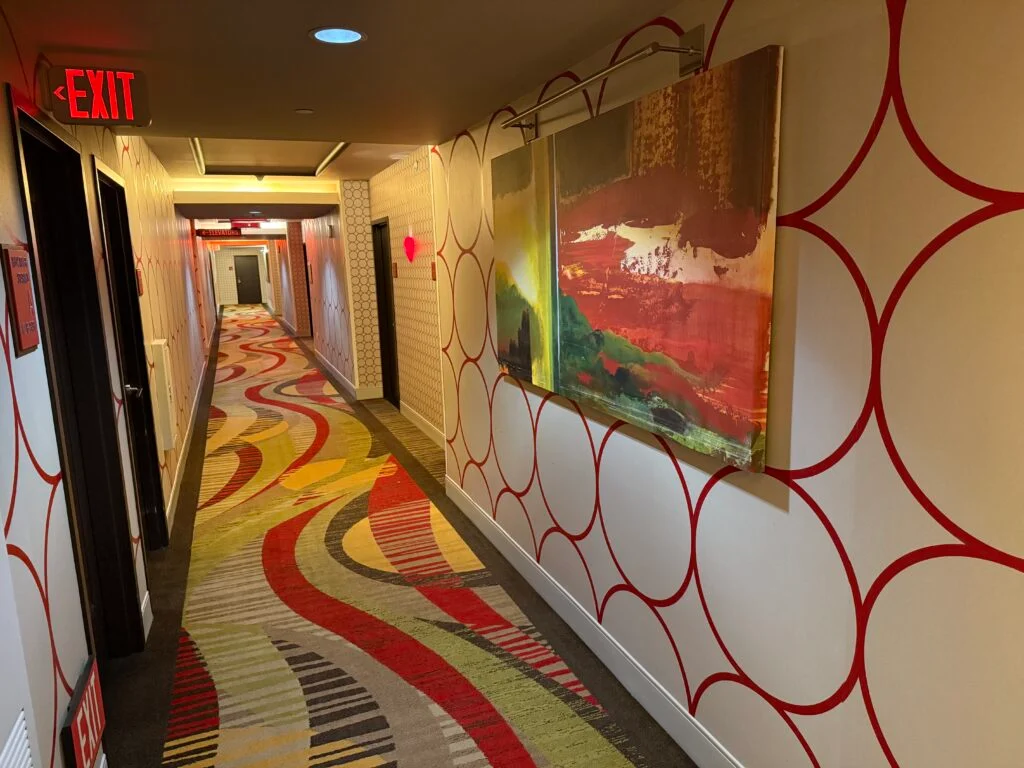 Hotel Hallway, with a painting on the wall, and a circle pattern on the wallpaper. 