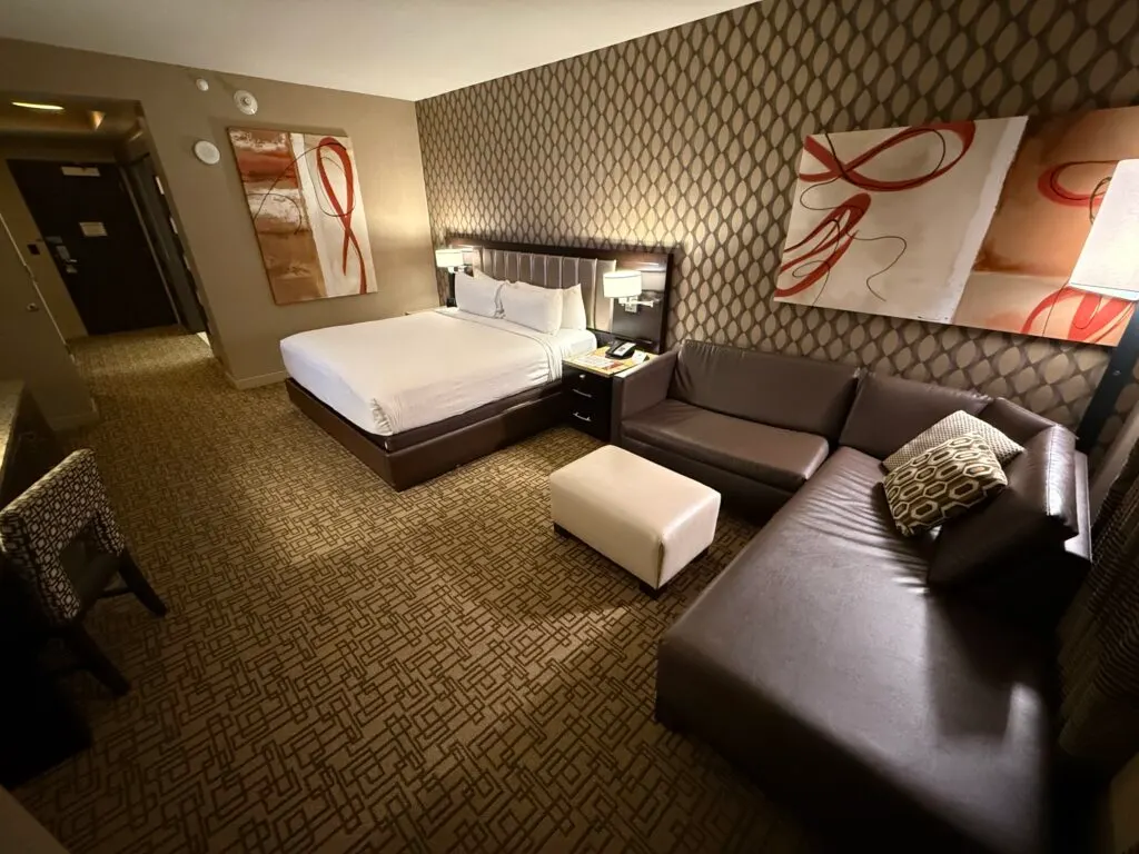 King bed in the background with an L shaped sectional couck in the foreground to the right. 