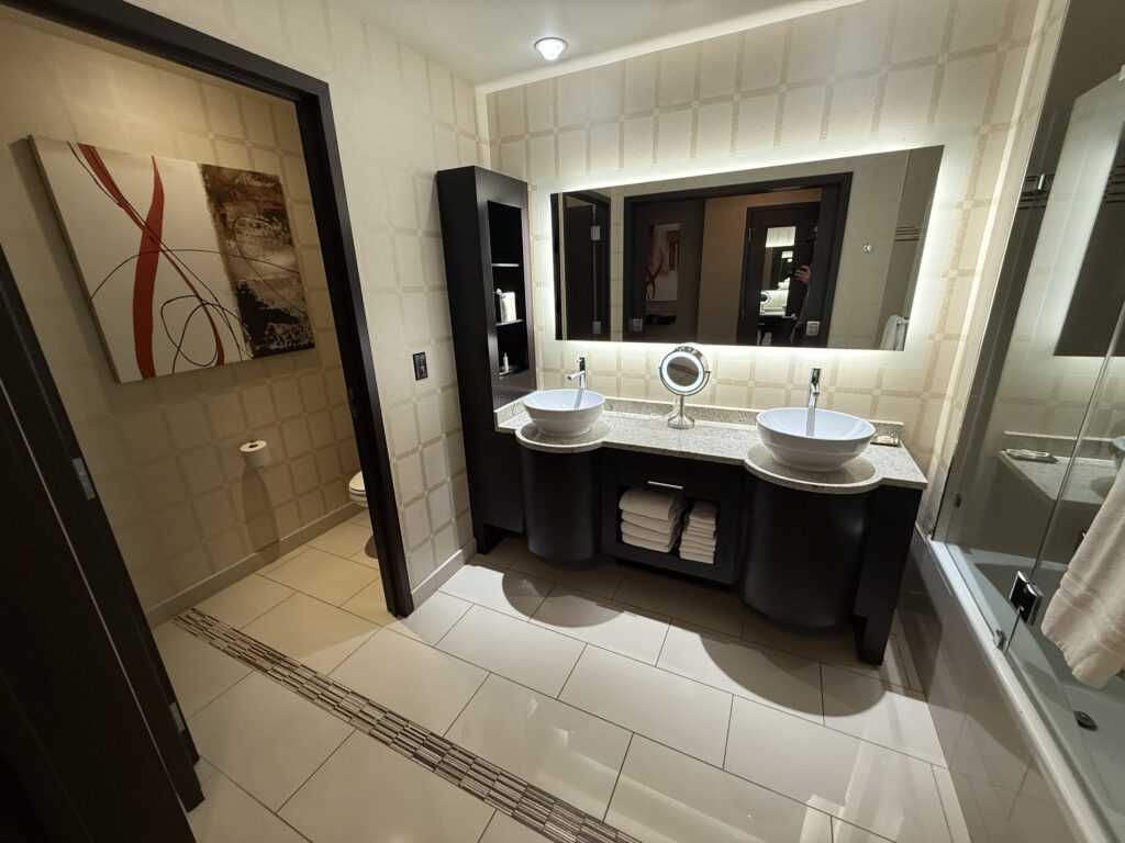 A dual sink vanity with a doorway to the toilet to the left.
