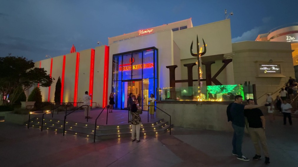 Exterior of Hell's Kitchen at night, illuminated, and the logo is aflame.
