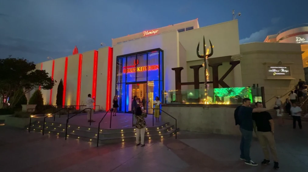 Exterior of Hell's Kitchen at night, illuminated, and the logo is aflame.