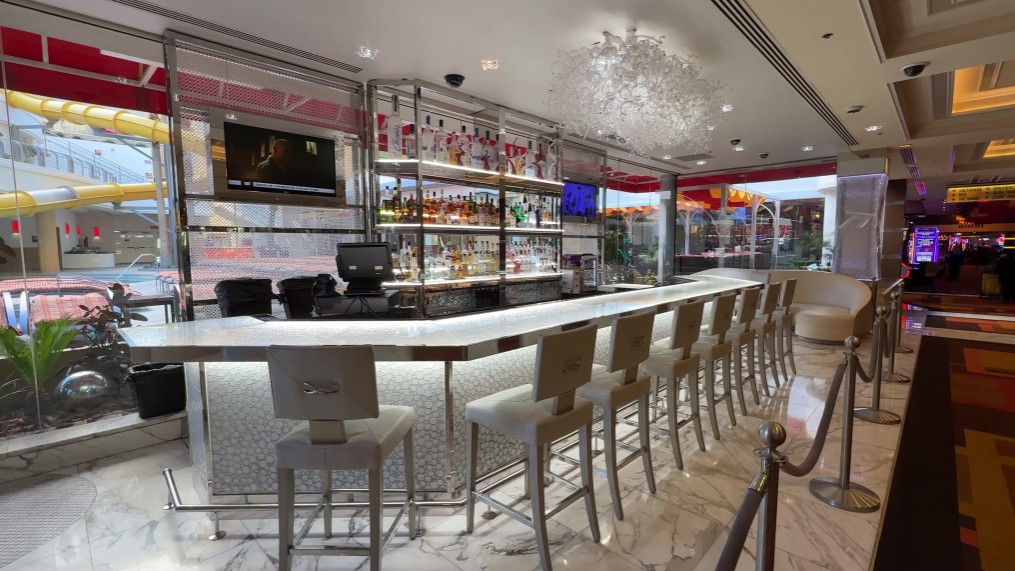 A bar overlooking the pool with a decorative white glass chandelier above it.