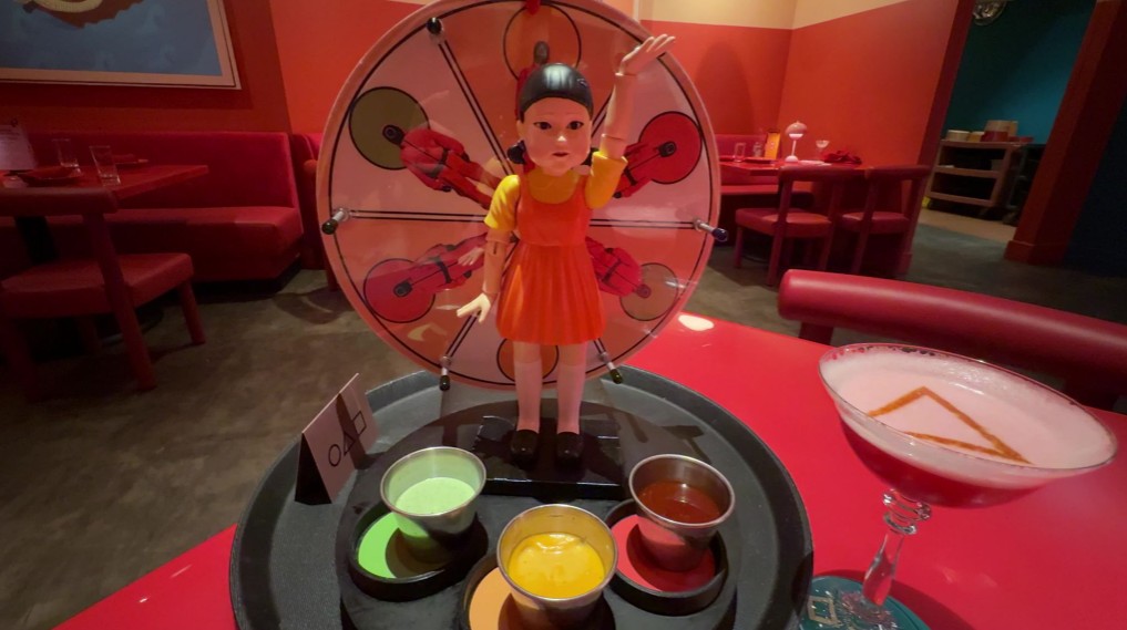 A vertical wheel facing the diner with different sauces on the spinner. At the base, are the sauces in little cups.