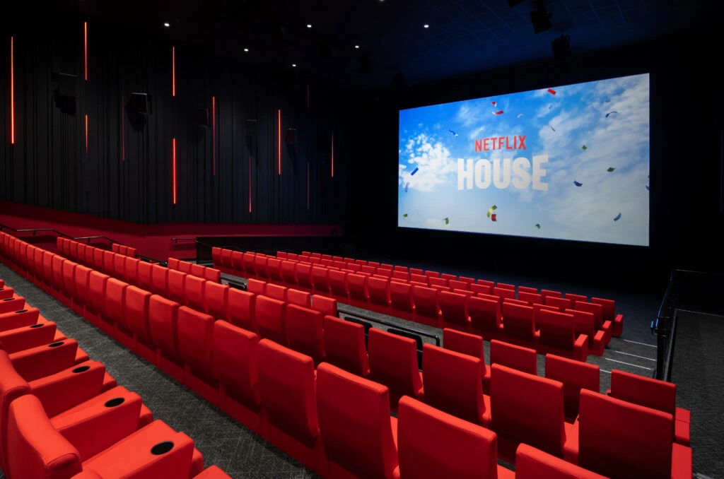 A theater with red seats pointing at a large screen.