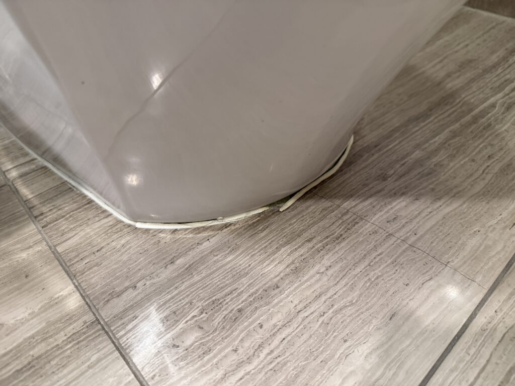 Damaged caulk at the base of the toilet.