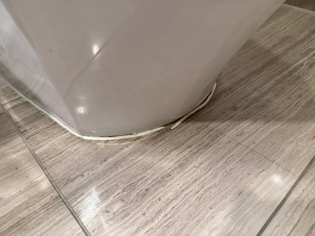 Damaged caulk at the base of the toilet.