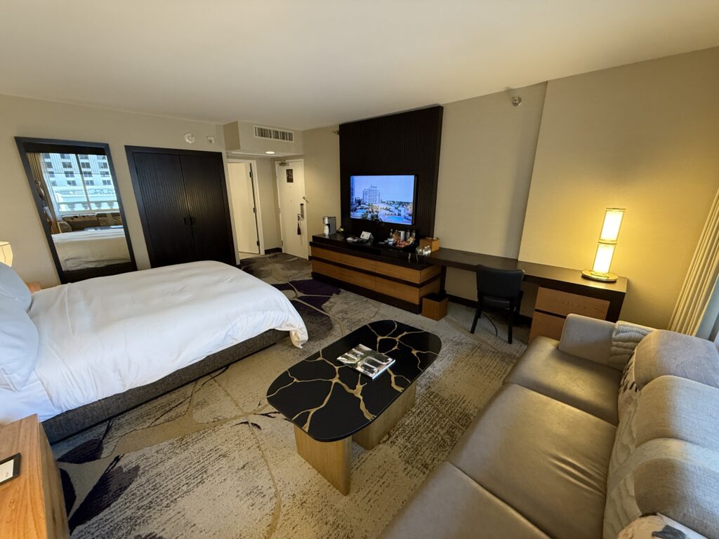 A final view that shows the bed pointed at the TV, but the couch and a coffee table in the foreground.