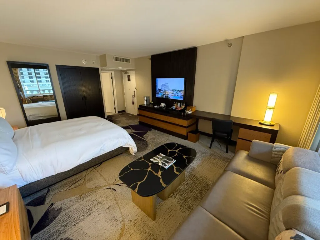 A final view that shows the bed pointed at the TV, but the couch and a coffee table in the foreground.