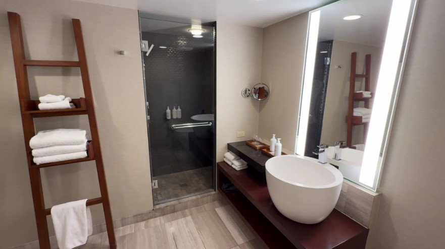 Single Sinke vanity right next to the shower exit and a towel rack.