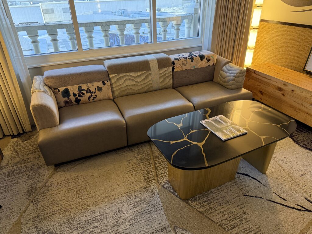 A couch with a chaotic design with various patterns on it and cushions of differing sizes.