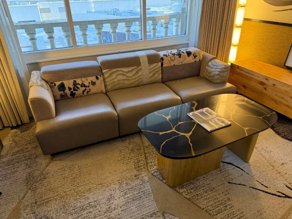 A couch with a chaotic design with various patterns on it and cushions of differing sizes.