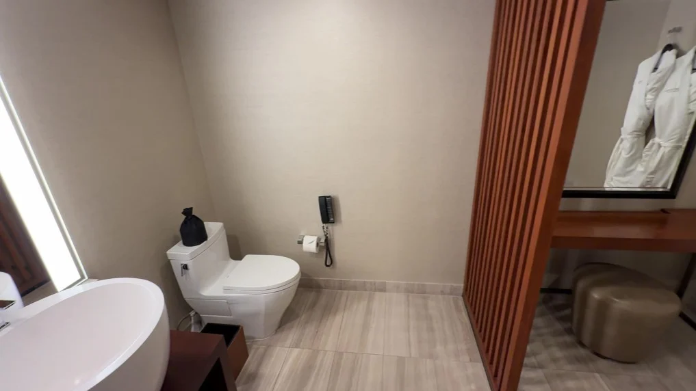 A toilet in the corner against the backdrop of plain, gray walls.