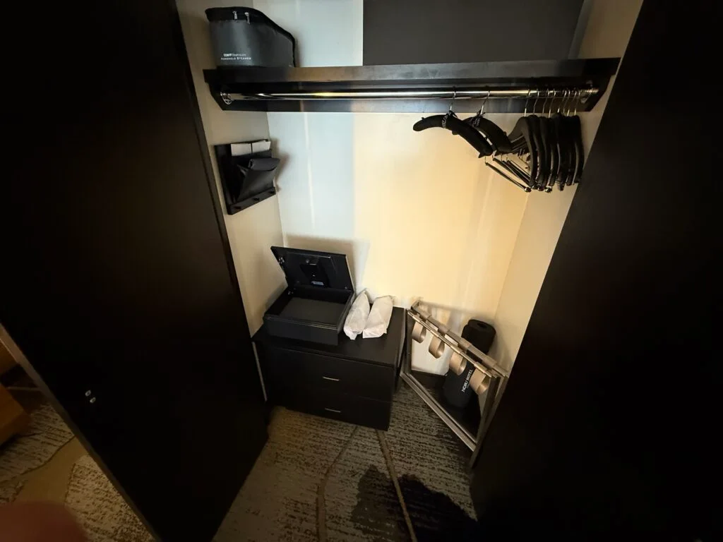 A closet in the room stocked with items like slippers, a yoga mat, and a steamer.