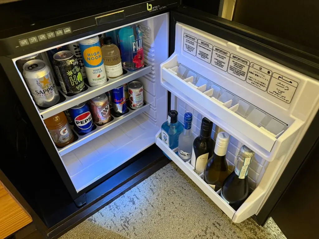 A fridge stocked with minibar items.