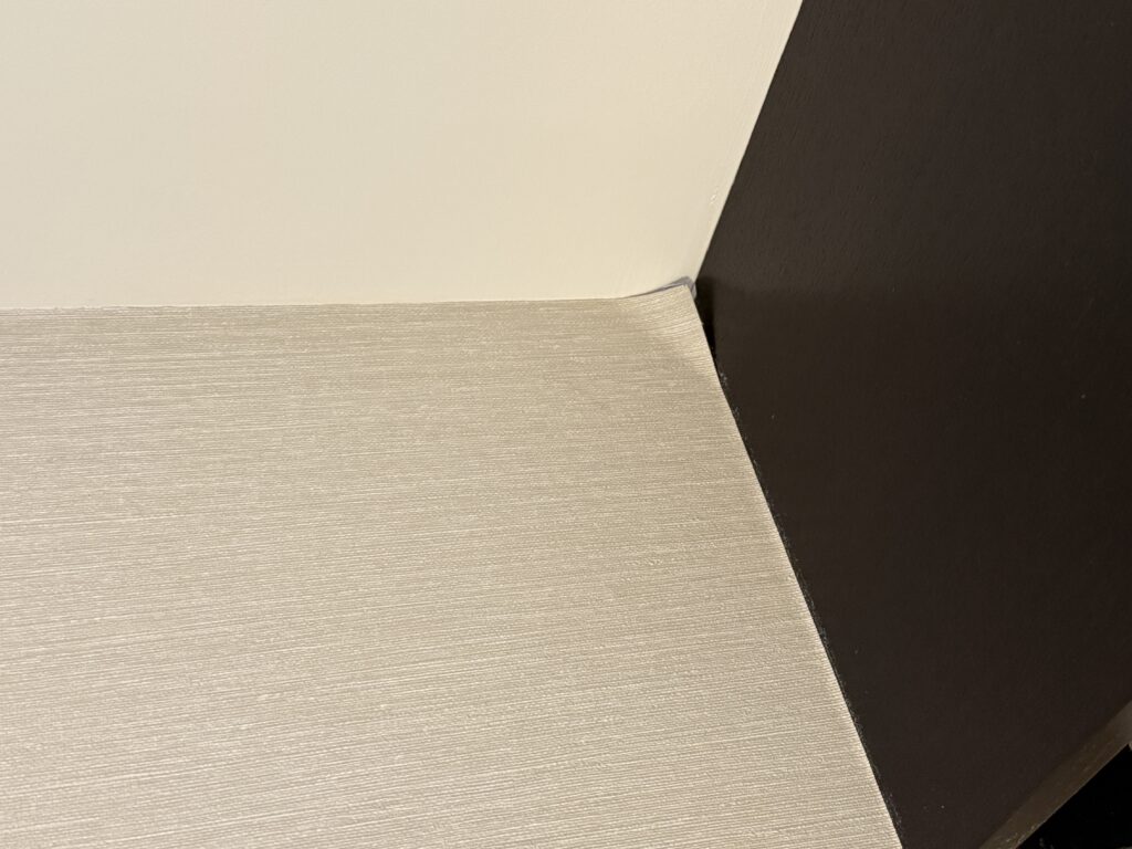 Wallpaper peeling away from the wall in a corner.