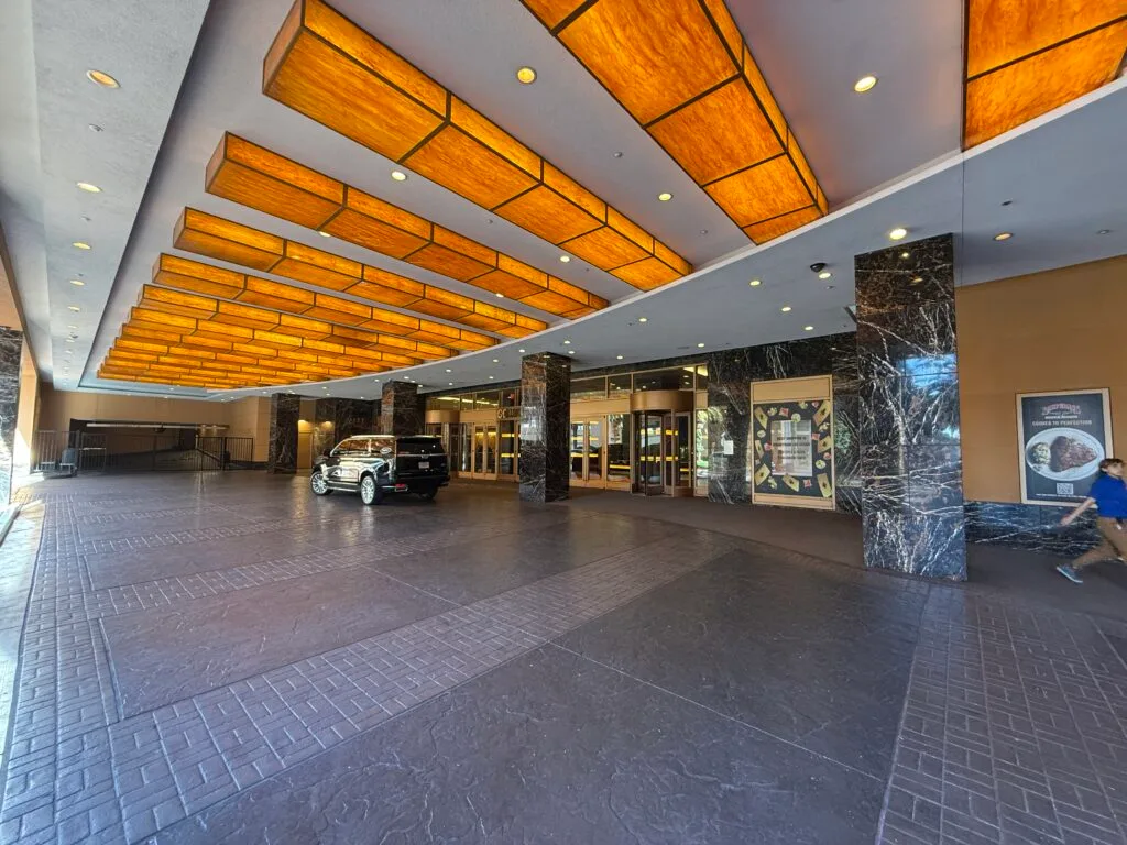 Underneath the Porte Cochere. Overhead are illuminated amber columns along the ceiling. 