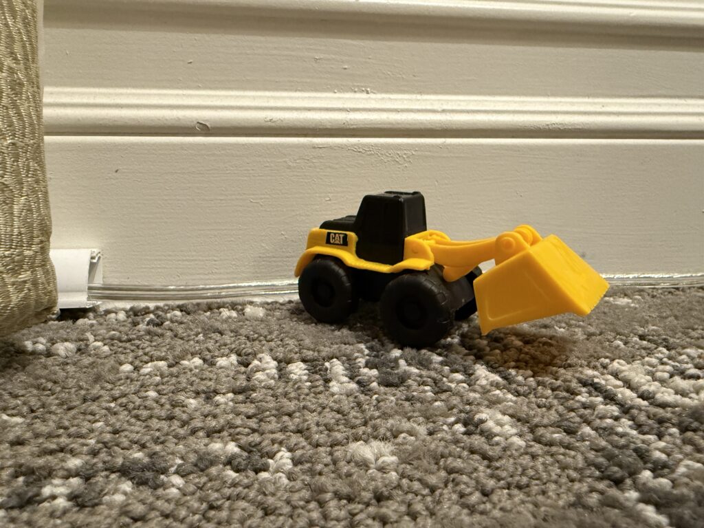 A toy bulldozer on the floor in my room.