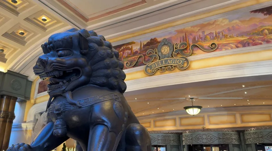 A black statue of a lion stands guard in front of Bellagio's entrance. 