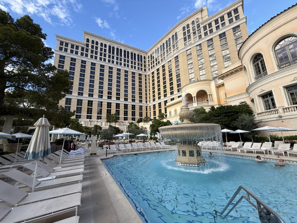 A pool with a fountain in the middle in front of Bellagio's hotel tower in the background.